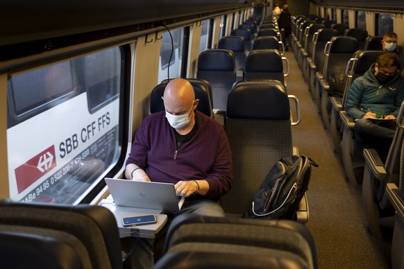 epa09091964 Passenger wearing protective mask works on a laptop as he rides a Swiss Federal Railways SBB CFF FFS train during the coronavirus disease (COVID-19) outbreak, in Neuchatel, Switzerland, 23 ...