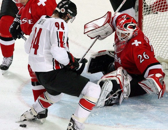 Switzerland's Martin Gerber (R) stop Canada's Ryan Smith (C) in front of the net during the Men's Preliminary Round game between Canada and Switzerland at the Turin 2006 Winter Olympic Games, in Turin ...