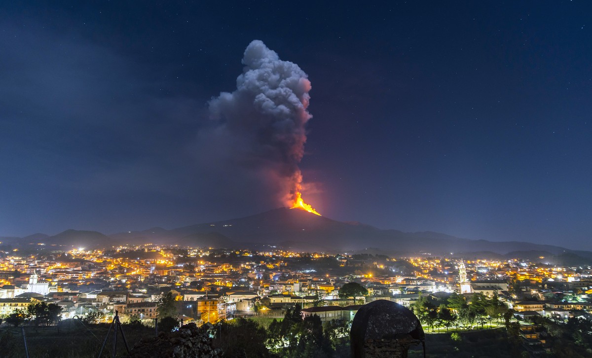 Flames and smoke billowing from a crater, as seen from the southern side of the Mt Etna volcano, tower over the city of Pedara, Sicily, Wednesday night, Feb. 24, 2021. Europe's most active volcan ...