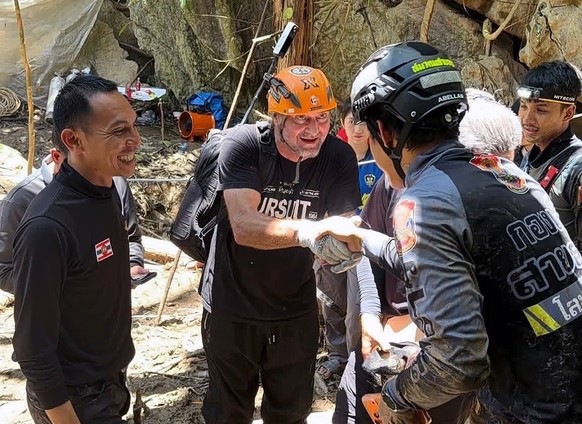 epa12994234 A handout photo made available by Metta Tham Kalasin Rescue shows Finnish expert diver Mikko Paasi (C) being greeted by Thai rescuers as he arrives to join a mission to rescue seven Laotia ...