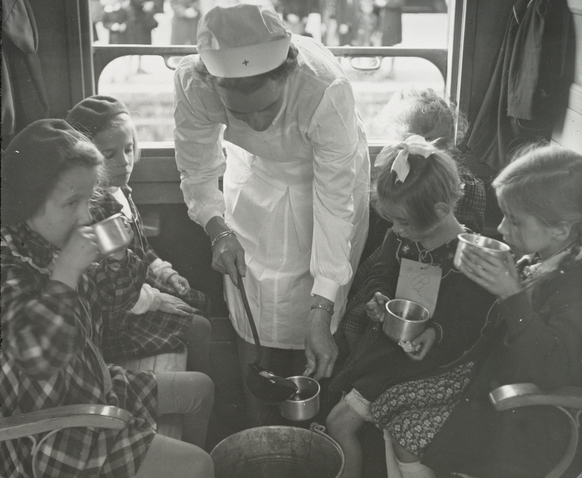 Eine Zugbegleiterin des SRK verpflegt Zugkinder auf Rückreise.