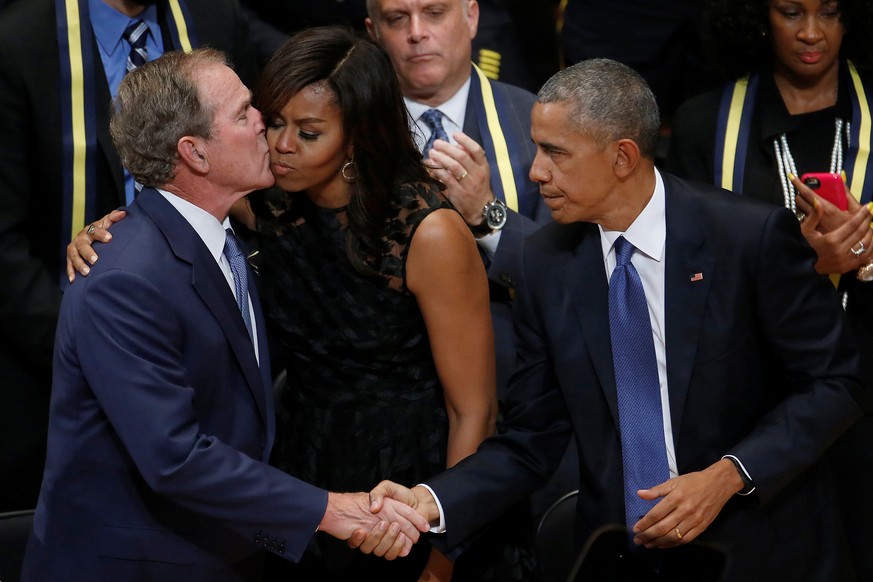 Am Rande der Gedenkfeier: George W. Bush küsst Michelle Obama und schüttelt Barack Obamas Hand.<br data-editable="remove">