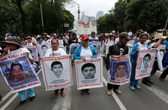 Relatives hold posters with images of some of the 43 missing students of Ayotzinapa College Raul Isidro Burgos as they take part in a march to mark the two-year anniversary of their disappearance of 4 ...