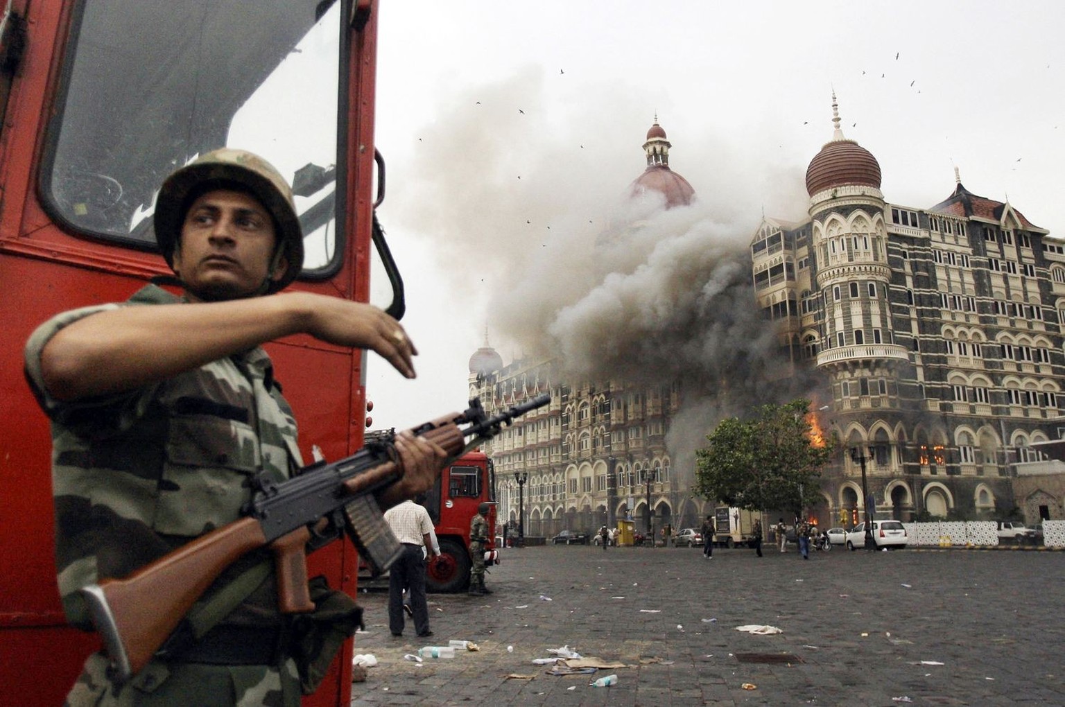 FILE- An Indian soldier takes cover as the Taj Mahal hotel burns during a gun battle between Indian military and militants inside the hotel in Mumbai, India, Nov. 29, 2008. The three days of terror in ...