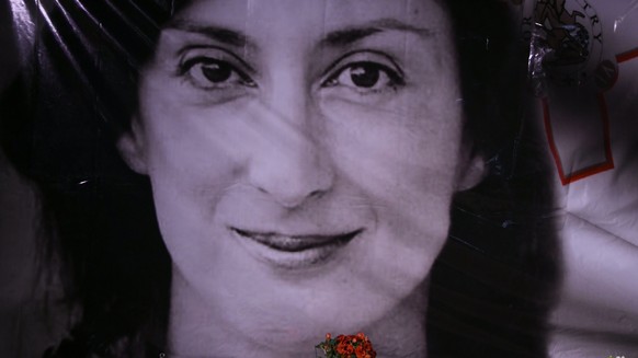 Flowers and a candle lie in front of a portrait of slain investigative journalist Daphne Caruana Galizia during a vigil outside the law courts in Valletta, Malta, Tuesday, Oct. 16, 2018. Caruana Galiz ...