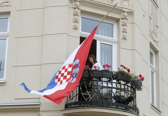 epa12056148 A woman stands on her balcony with a Croatian flag flown at half-mast during a day of Mourning for the late Pope Francis in Zagreb, Croatia, 26 April 2025. The Croatian government declared ...