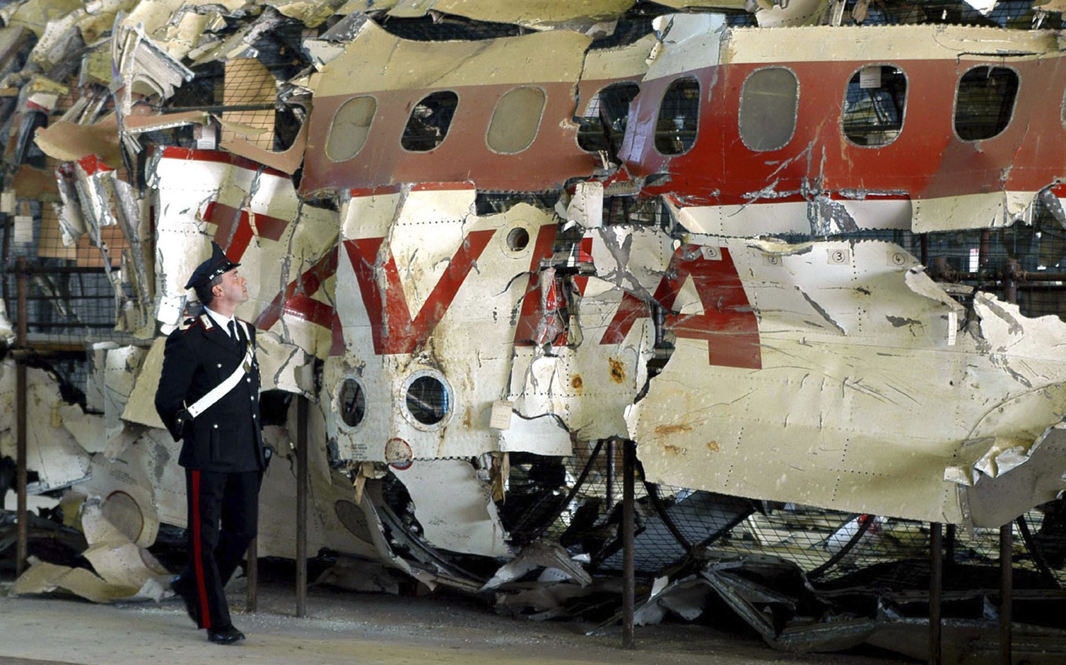FILE - An Italian Carabinieri police officer patrols a hangar, in Pratica di Mare, near Rome, Monday Dec. 15, 2003, the reconstructed wreckage of the Itavia DC-9 passenger jetliner which crashed near  ...