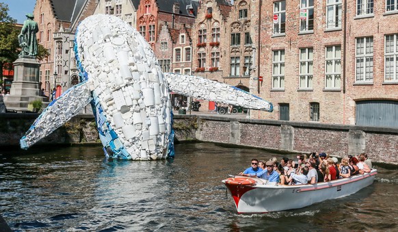 epa06921804 A boat of tourists sails past a 12-metre installation depicting a whale, made up of five tons of plastic waste pulled out of the Pacific Ocean, displayed in Bruges, Belgium, 01 August 2018 ...