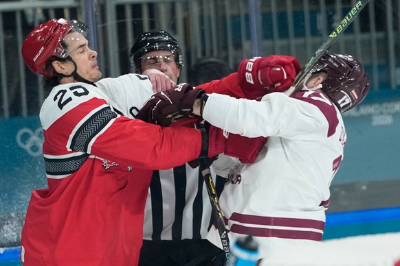 Denmark's Oliver Lauridsen, left, challenges Latvia's Martins Dzierkals during a preliminary round match of men's ice hockey between Denmark and Latvia at the 2026 Winter Olympics, in M ...