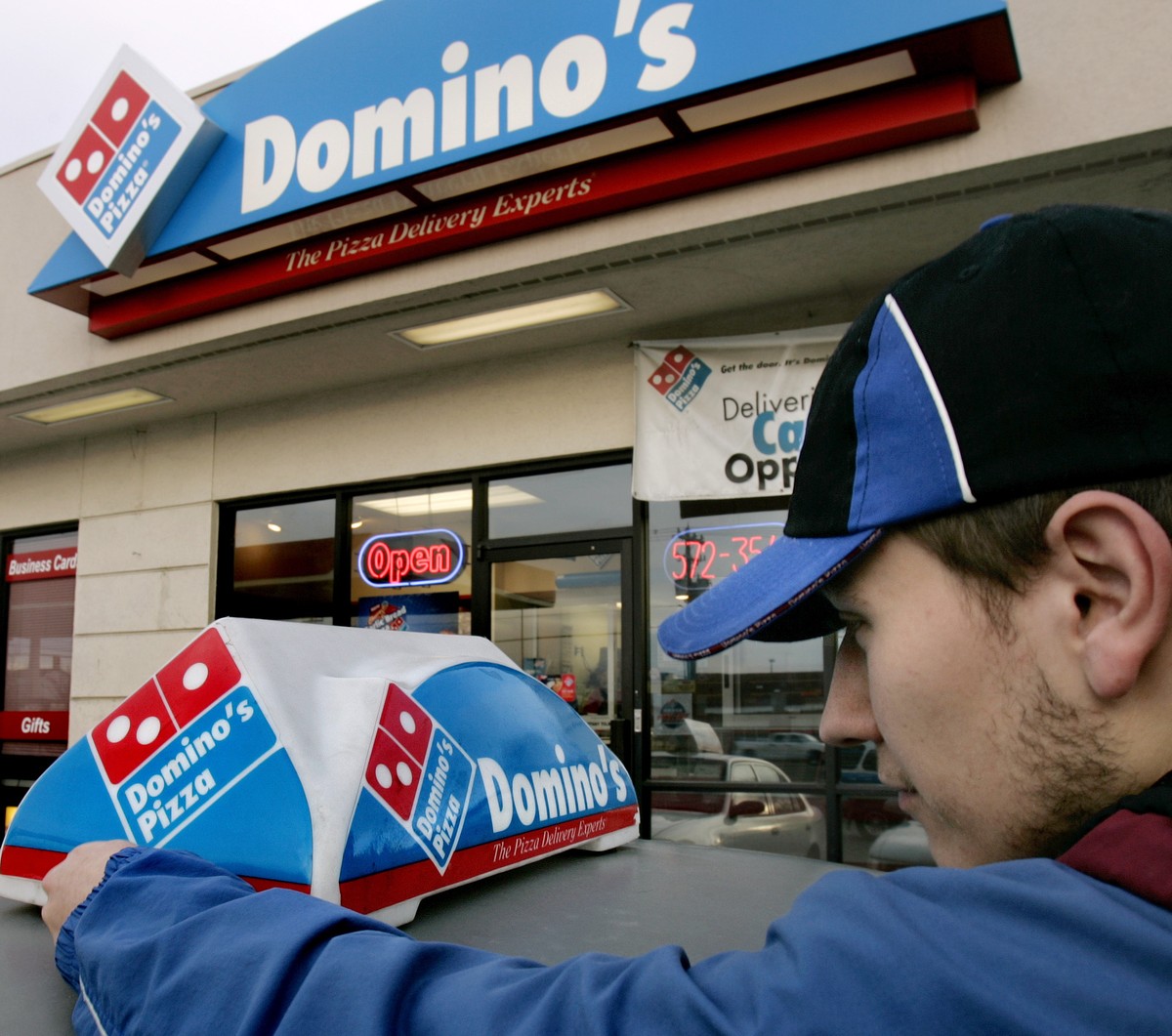 FILE - In this Feb. 21, 2007 file photo, Domino's Pizza delivery person Brandon Christensen plugs in the company sign atop his car in Sandy, Utah. The pizza delivery chain on Monday, June 16, 201 ...