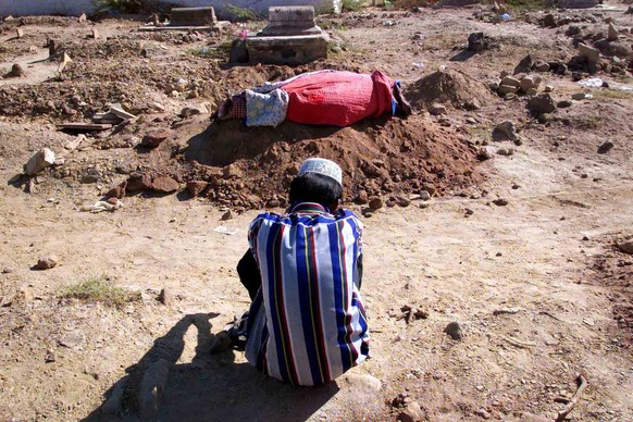 Mohin Ali Mohamad, 22, sits in front of the bodies of his father and sister, wrapped together for burial in Bhuj, India Tuesday, Feb, 6, 2001. Hundreds of thousands of people are either homeless or li ...