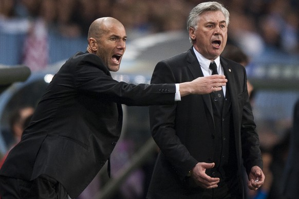 Real Madrid&#039;s assistant coach Zinedine Zidane from France, left, and coach Carlo Ancelotti from Italy, right, gesture during a Spanish La Liga soccer match at La Rosaleda stadium in Malaga, Spain ...