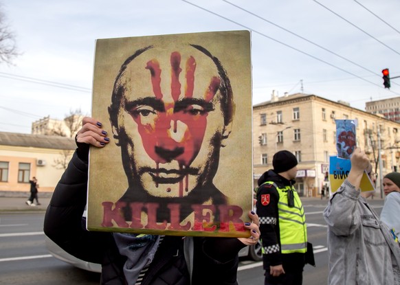 epa11179363 A woman holds a sign with the image of Russian President Putin during a protest in front of the Russian Embassy to mark the second anniversary of the Russian invasion of Ukraine, in Chisinau, M...