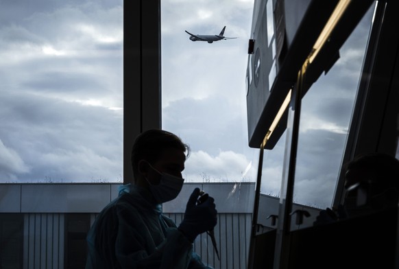 Ein Labor-Mitarbeiter verarbeitet Corona-Proben in einem Labor am Flughafen Zuerich, am Donnerstag, 2. Dezember 2021 in Zuerich. Das neu eroeffnete Flyender Labor bietet nach eigenen Angaben die schne ...