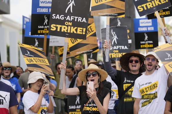 File - People picketing on behalf of the Screen Actors Guild-American Federation of Television and Radio Artists carry signs outside Netflix on Sept. 27, 2023, in Los Angeles. From auto production lin ...