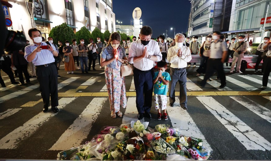 People pray at a makeshift memorial at the scene where the former Prime Minister Shinzo Abe was shot while delivering his speech to support the Liberal Democratic Party&#039;s candidate during an elec ...