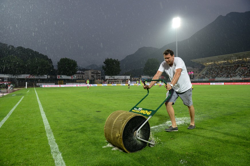 A worker trys to get water of the field during the brake of the game FC Lugano against FC St. Gallen after havy rainfalls, at the Cornaredo stadium in Lugano, Saturday, July 29, 2017. (KEYSTONE/Ti-Pre ...