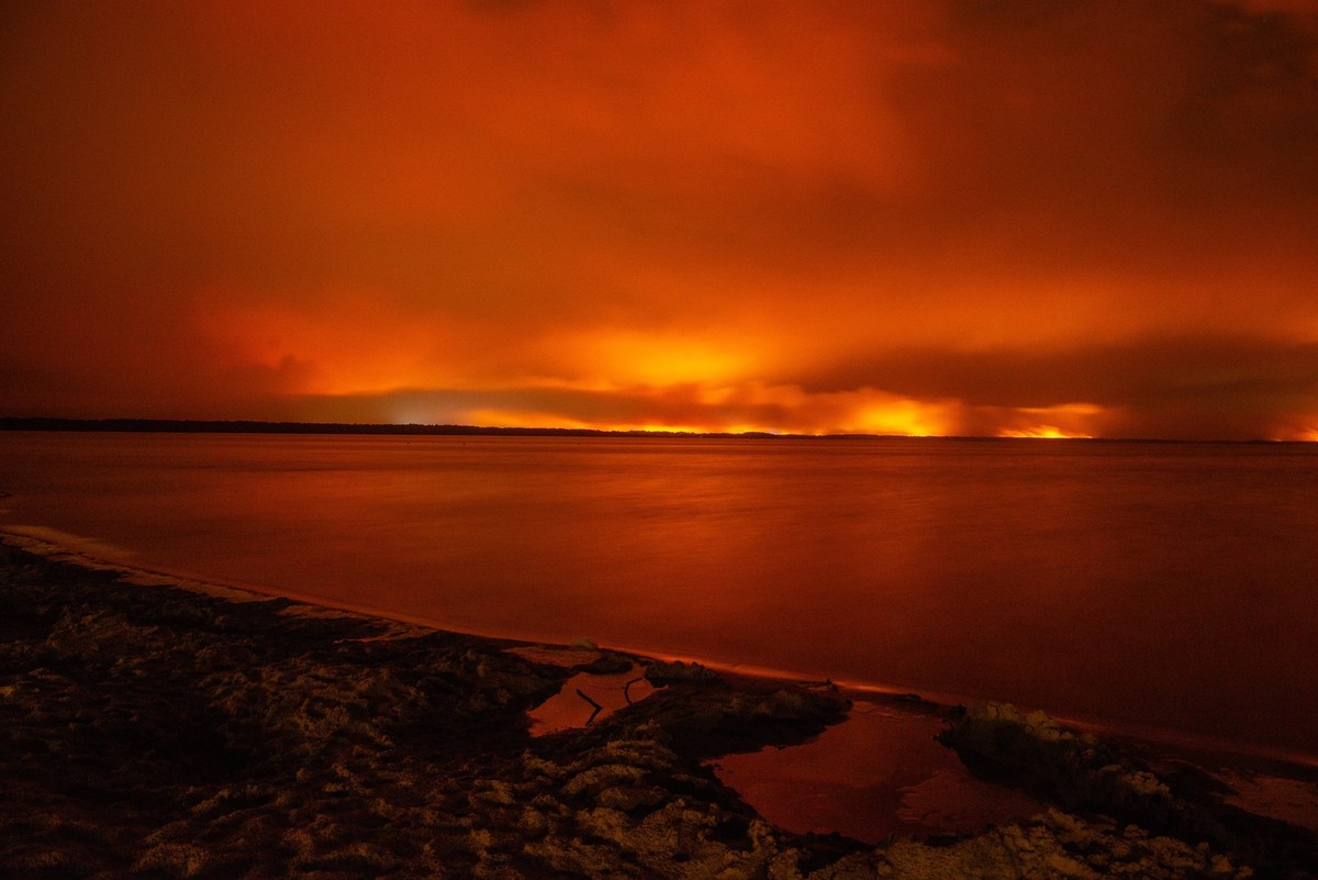 Wildfires in France Drive 250,000 People from Their Homes - Gironde The sky glows deep red over Lake Moutchic as the Lège-Cap-Ferret wildfire illuminates the horizon in Gironde, France on July 25, 202 ...