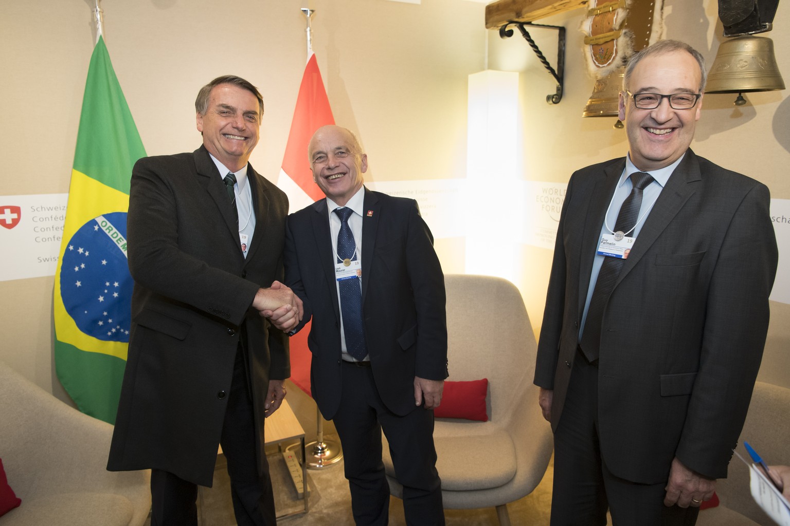 Brazil&#039;s President Jair Bolsonaro, left, shakes hands with Swiss Federal President Ueli Maurer, centre, next to Swiss Federal Councillor Guy Parmelin, right, during a bilateral meeting on the sid ...