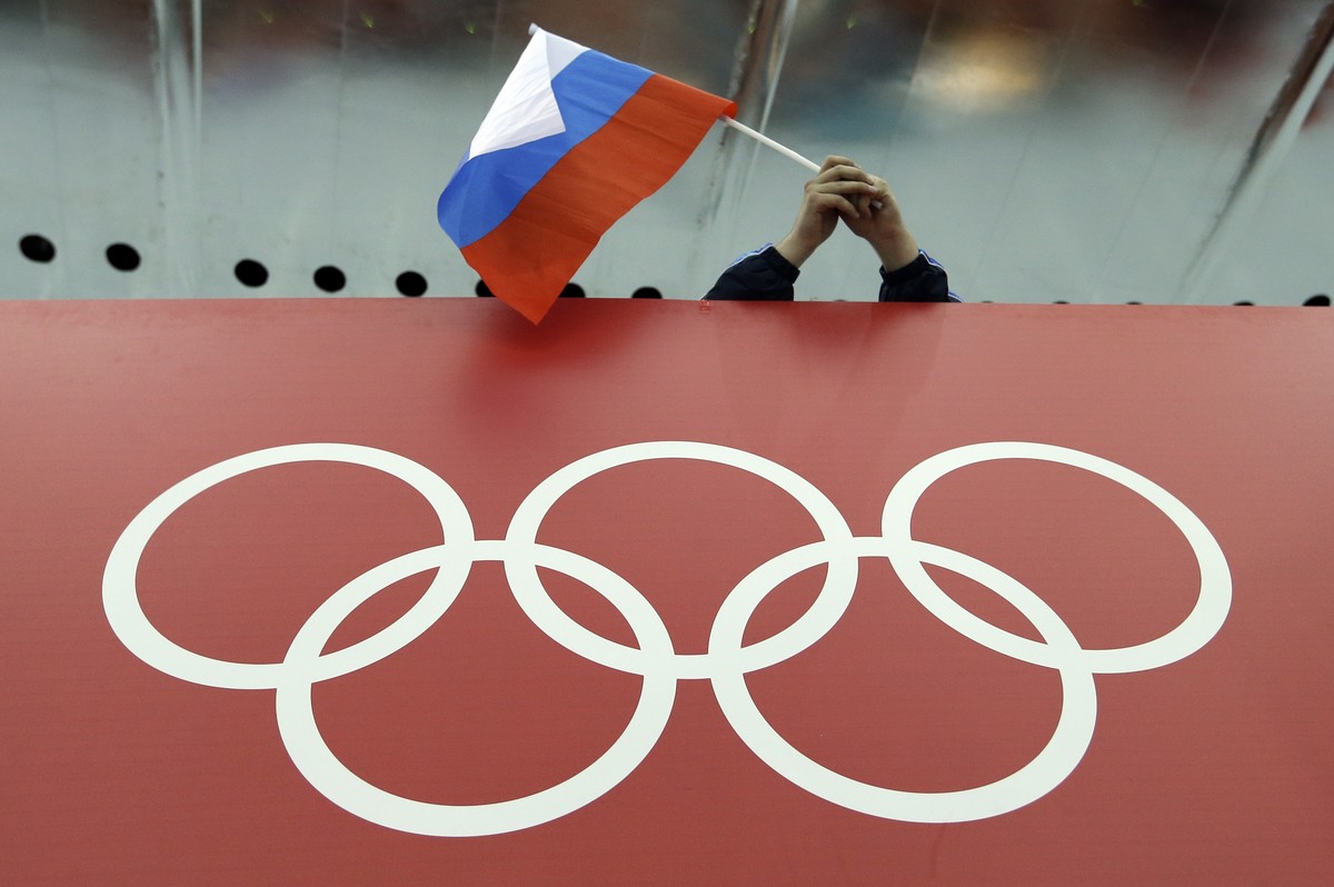 FILE - In this Feb. 18, 2014, file photo, a Russian skating fan holds the country's national flag over the Olympic rings before the start of the men's 10,000-meter speedskating race at Adler ...