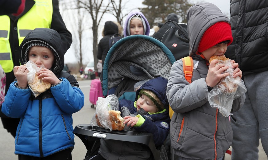 epa09789835 Ukrainian refugee kids eat some snacks they received from volunteers after passing the Romanian-Ukrainian border crossing point in Siret, northern Romania, 27 February 2022. Romanian autho ...