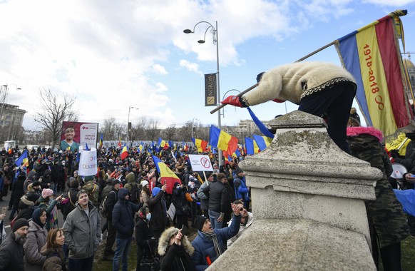 An anti-COVID-19 green pass protester climbs the fence of the Palace of Parliament in Bucharest, Romania, Tuesday, Dec. 21, 2021. People gathered to protest against the introduction of the COVID-19 &q ...
