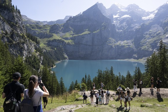 Tourists enjoying the sunshine above the lake of Oeschinen &quot;Oeschinensee&quot; (1578 meters above sea), during a very hot summer day, above Kandersteg, in the Bernese Oberland, this August 9, 202 ...