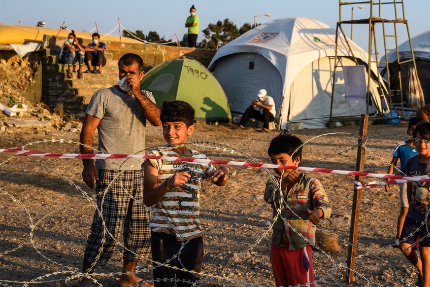 epa08682489 Adults and minors refugees and migrants stand behind razor wire at Kara Tepe camp on Lesbos island, Greece, 19 September 2020. Following the catastrophic fires at Moria on September 8 and  ...