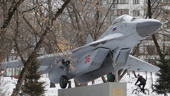 epa10454425 A man rides a bicycle next to a Soviet-made MiG-29 multirole fighter installed as a monument on Fedora Poletayeva Square in Moscow, Russia February 08, 2023. Temperatures in Moscow reached ...