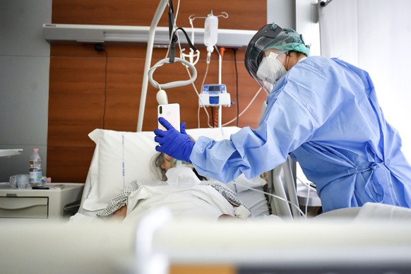 A medical staffer holds up a phone in front of a Covid-19 patient for a video call with relatives at Bergamo&#039;s Papa Giovanni XXIII hospital, northern Italy, Friday, April 3, 2020. The new coronav ...