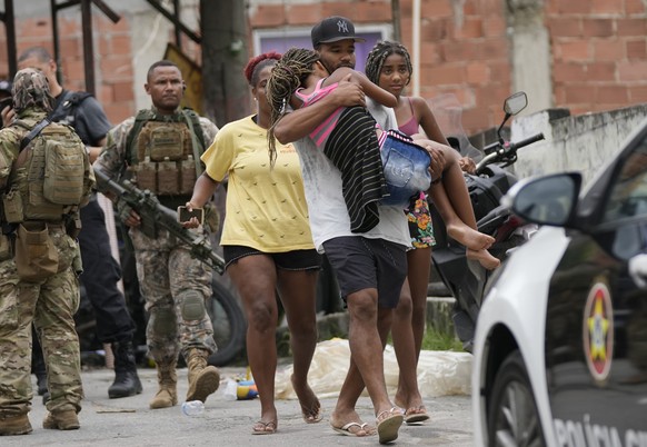 A man carries a young woman away from the scene of a deadly operation against alleged drug traffickers in the Vila Cruzeiro favela of Rio de Janeiro, Brazil, Friday, Feb. 11, 2022. The operation left  ...