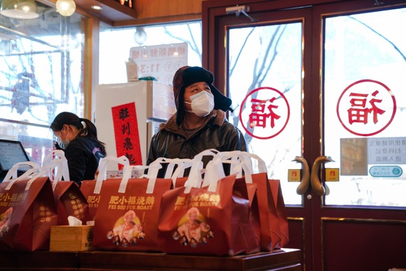 epa10354527 A man wearing a face mask waits for his take-out food in a restaurant in Beijing, China, 08 December 2022. Despite daily cases increasing, Chinese officials announced an easing of the COVI ...
