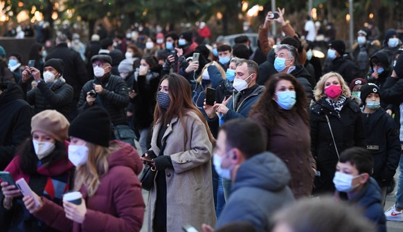 epa08868908 People wearing face masks take photos of the Christimas Tree set up in Piazza del Duomo (Cathedral square), the vital center of the city, a meeting point for the Milanese to celebrate impo ...