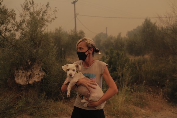 epaselect epa09406429 A local resident holds her dog that was rescued by locals during a wildfire at the village of Pefki in the Evia, Greece, 08 August 2021. Fires that broke out in Attica and Evia i ...