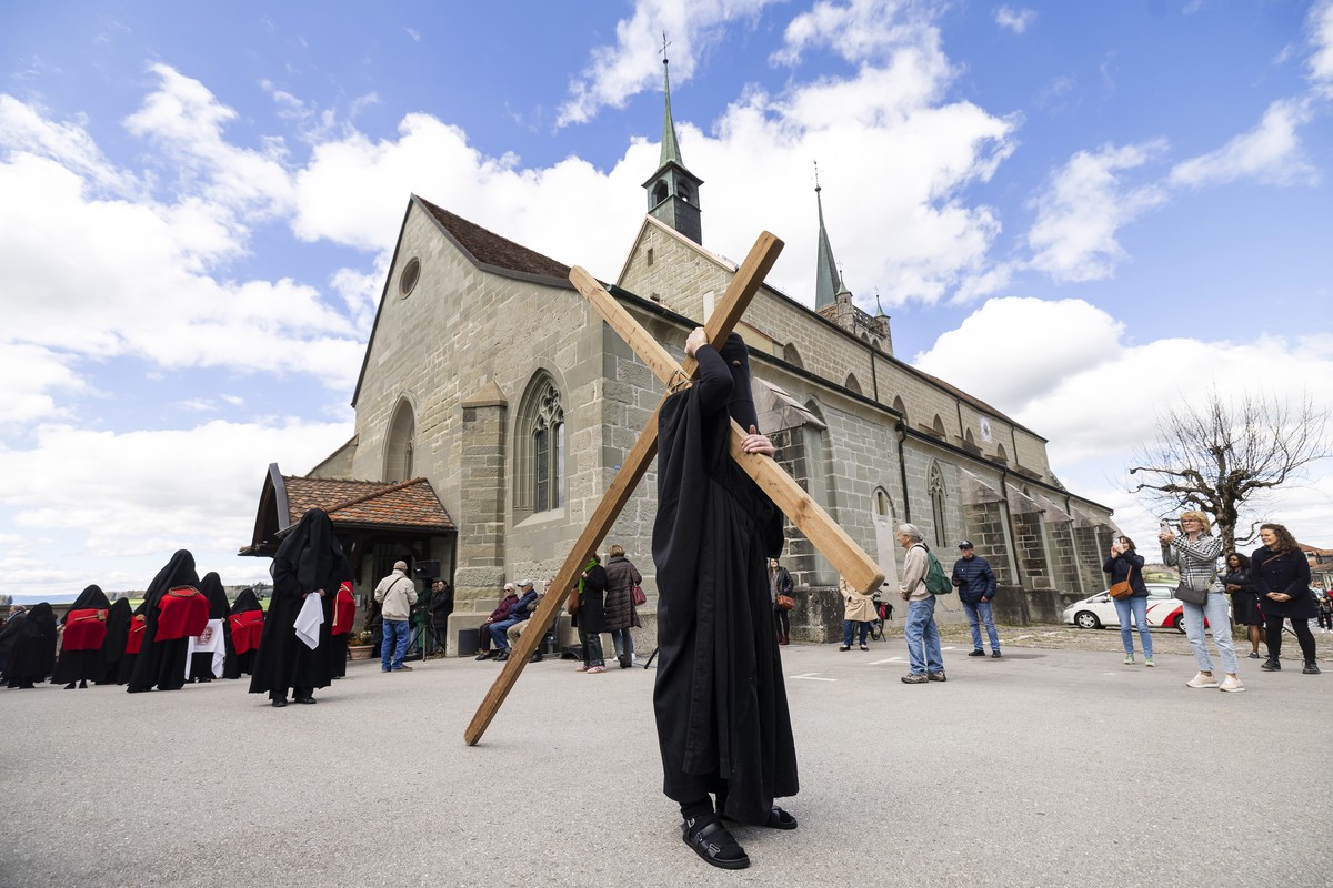 A cross bearer is followed by women dressed in black veils, know as "Les Pleureuses", walk around the Collegiale de Notre-Dame de l'Assomption during the Good Friday mass, in Romont , F ...