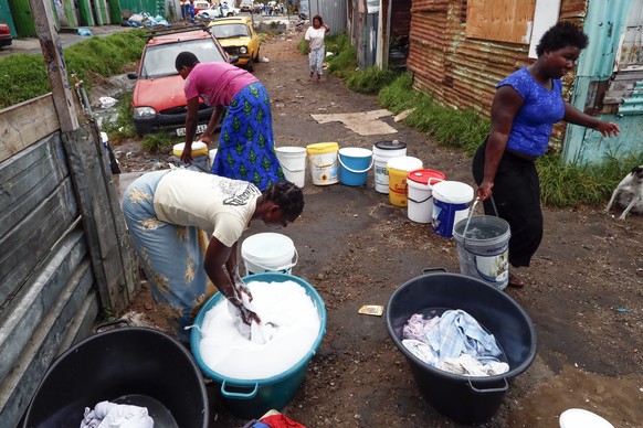 epa06485094 Residents of Masiphumelele informal settlement collect drinking water and wash clothes using water from a communal municipal tap in Cape Town, South Africa, 30 January 2018. For millions o ...