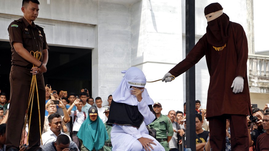 epa06680856 An Acehnese woman covers her face as she is caned in public for violating sharia law in Banda Aceh, Indonesia, 20 April 2018. Aceh&#039;s provincial government has decided to end the canin ...