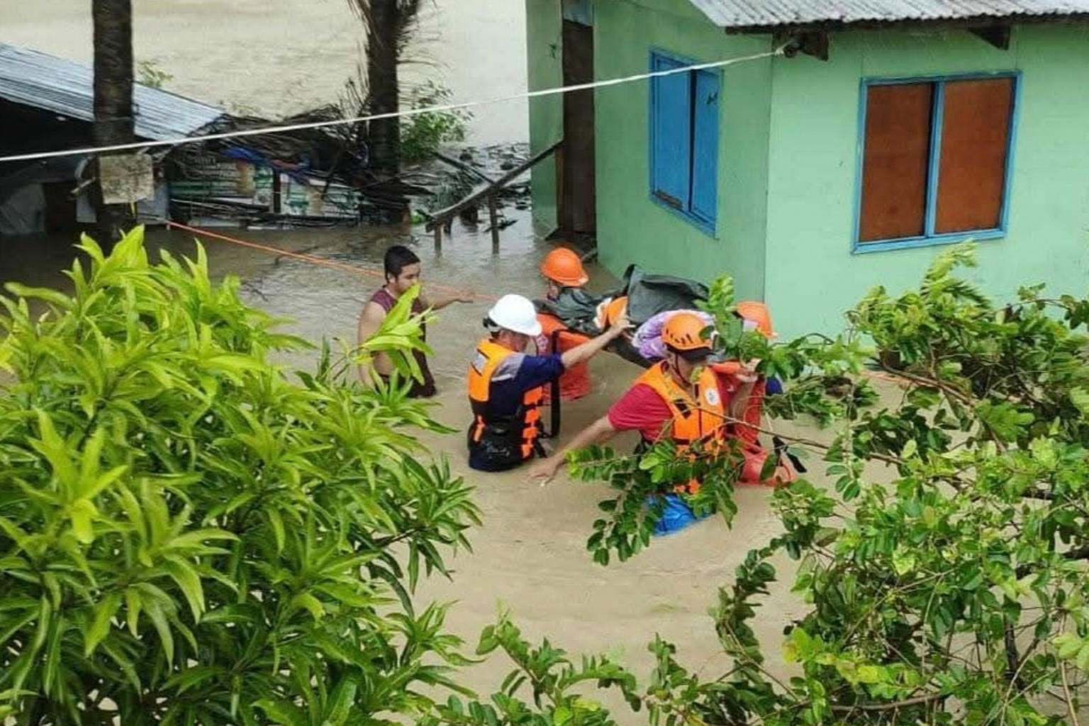 In this handout provided by the Philippine Coast Guard, rescuers evacuate a resident to safer grounds as floods rise due to Tropical Storm Bualoi in Odiongan, Romblon province, Philippines on Friday S ...