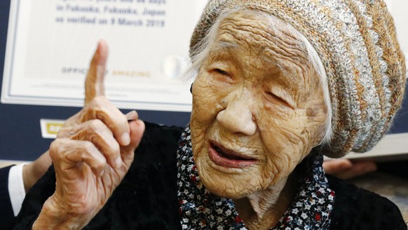 Kane Tanaka, a 116-year-old Japanese woman, gestures after receiving a Guinness World Records certificate, back, at a nursing home where she lives in Fukuoka, southwestern Japan, Saturday, March 9, 20 ...