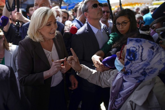 French far-right leader Marine Le Pen, left, talks to a woman as she campaigns in a market in Pertuis, southern France, Friday, April 15, 2022. (AP Photo/Daniel Cole)
Marine Le Pen