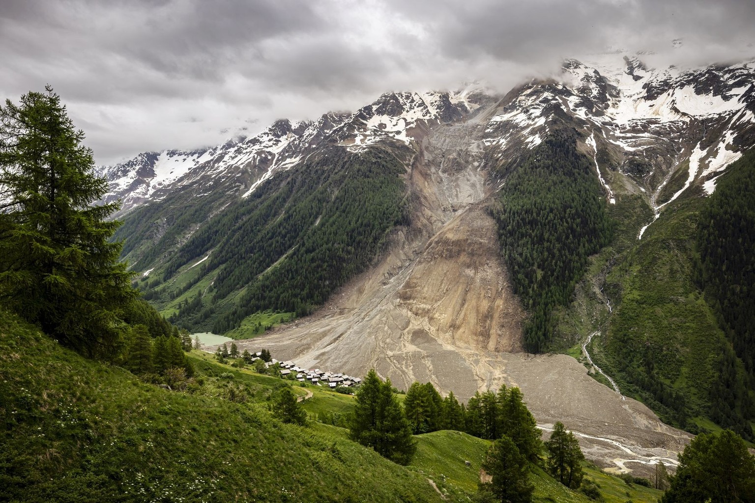 The hamlet of Wyssried, center, is seen above a massive avalanche, triggered by the collapse of the Birch Glacier, as it swept down to the valley floor and buried the village of Blatten, Switzerland,  ...