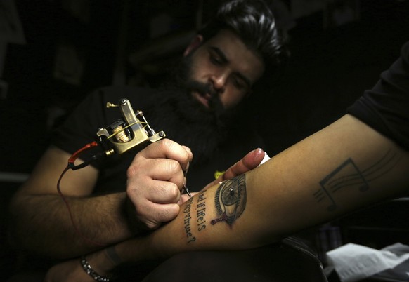 In this Tuesday. Oct. 23, 2018, photo, a man gets a tattoo on his arm in a tattoo studio in Baghdad, Iraq. One tattoo shop owner said he receives an average of 20 persons a year who want to cover thei ...