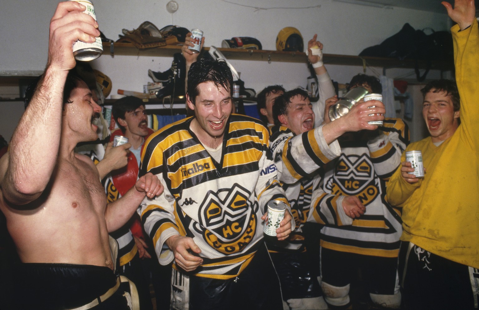 Die HC Lugano-Eishockeyspieler Beat Eggimann, Alfred Luethi, Andy Ton und Bernasconi feiern am 25. Maerz 1987 in der Garderobe im Stadion La Resega nach dem entscheidenden gewonnenen Playoff-Spiel geg ...