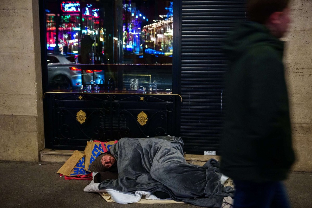 Un sans-abri dort sur un trottoir sous une couverture dans le centre de Paris, le 27 décembre 2025.