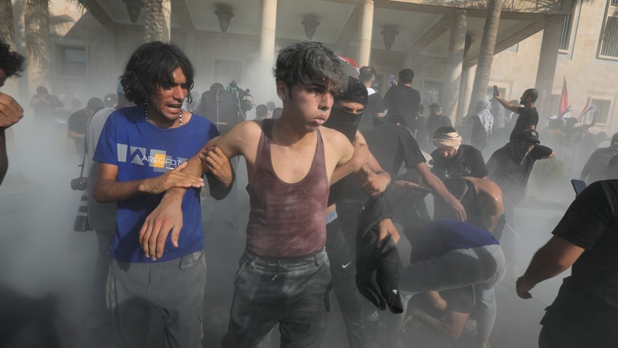 epa10145986 Supporters of Iraqi Shiite cleric Muqtada al-Sadr help injured protesters during clashes with anti-riot forces near the office of prime minister, Baghdad, Iraq, 29 August 2022. Several peo ...