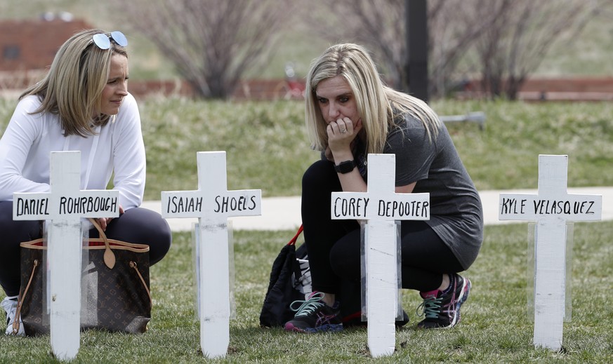Cassandra Sandusky, right, a graduate of Columbine High School, pauses with her friend, Jennifer Dunmore, at a row of crosses bearing the names of the victims of the attack at the school 20 years ago  ...