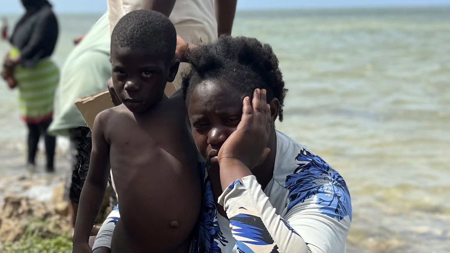 epa10770031 A woman sits with a boy among Sub-Saharan African migrants who were expelled from the city of Sfax in Tunisia gather in an area near the Libyan-Tunisia border, in Ras Jedir, 173 km west of ...