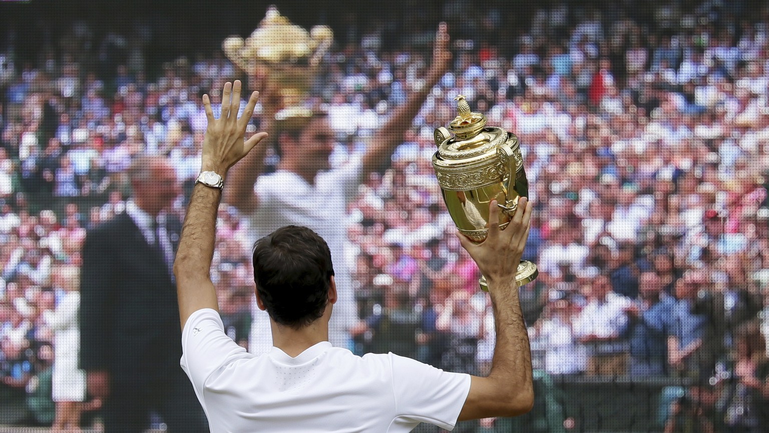 Switzerland&#039;s Roger Federer holds the trophy in front of a television screen after defeating Croatia&#039;s Marin Cilic to win the Men&#039;s Singles final match on day thirteen at the Wimbledon  ...