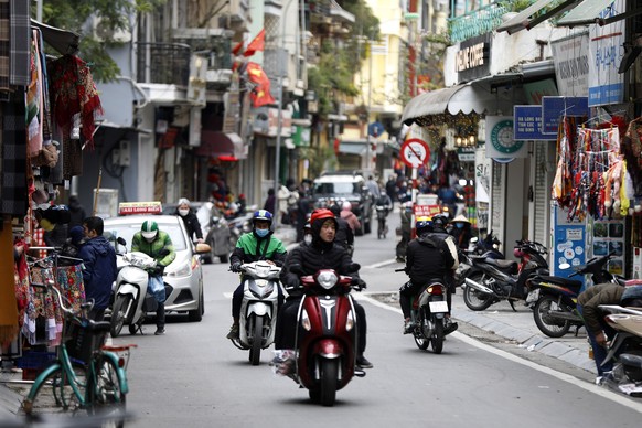 epa09776787 People ride motorbikes at a street in Hanoi, Vietnam, 22 February 2022. Vietnam confirms 55,871 new domestic Covid-19 cases on 22 February, the highest number of daily infections so far, a ...