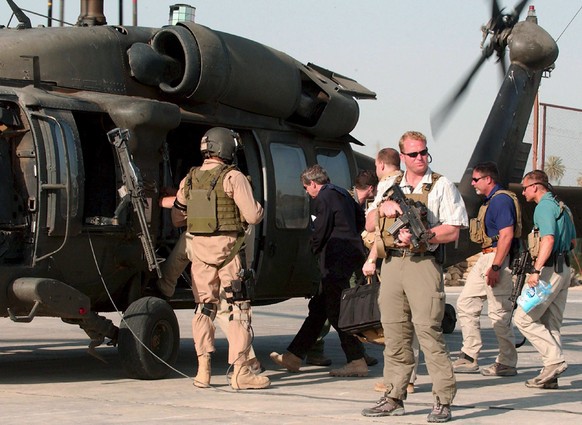 epa04703774 (FILE) A file picture dated 17 June 2007 shows U.S. administrator Paul Bremer (C) guarded by private US security company personnel boarding a helicopter in the Iraqi city of Hillah. A fede ...